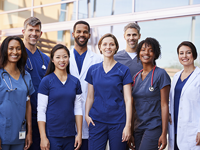 Smiling medical team standing together outside a hospital Hands holding